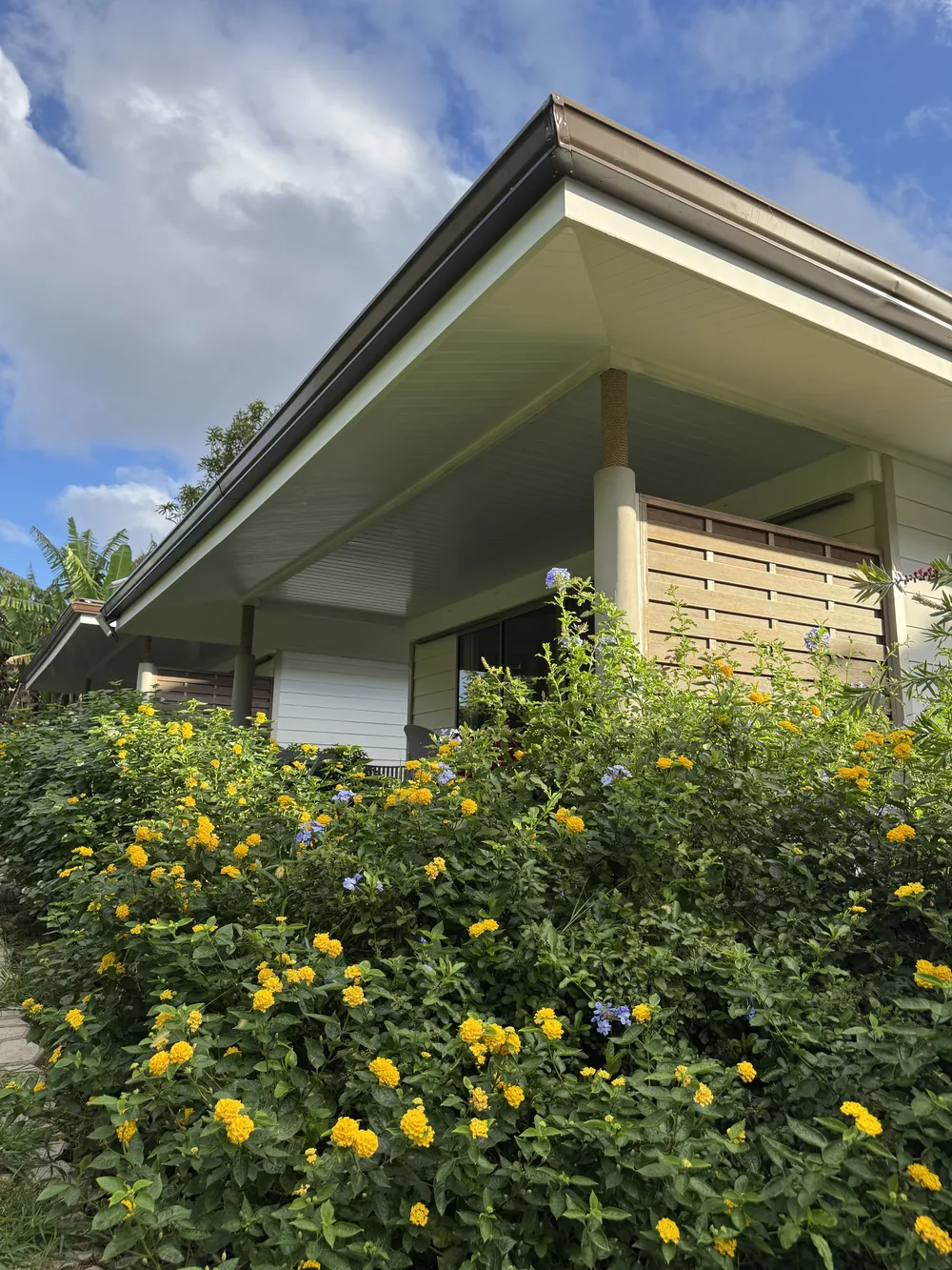 Un bungalow du Fare Manini derrière les massifs fleuris du jardin